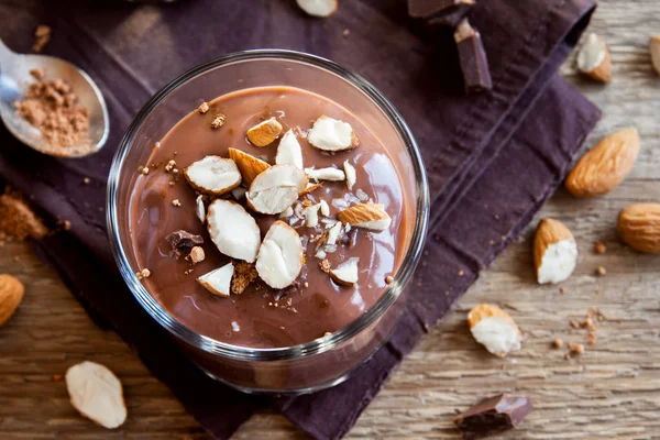 Sağlıklı çiğ Vegan çikolata badem ile tepesinde camlar ahşap arka plan üzerinde köpük yakın çekim - lezzetli ev yapımı çiğ Vegan çikolatalı puding ile fındık ve keçiboynuzu tozu