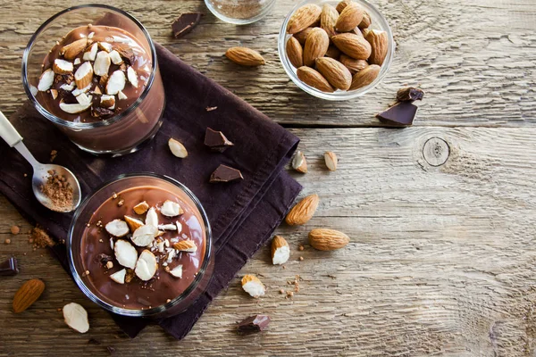 Sağlıklı çiğ Vegan çikolata badem ile tepesinde camlar ahşap arka plan üzerinde köpük yakın çekim - lezzetli ev yapımı çiğ Vegan çikolatalı puding ile fındık ve keçiboynuzu tozu