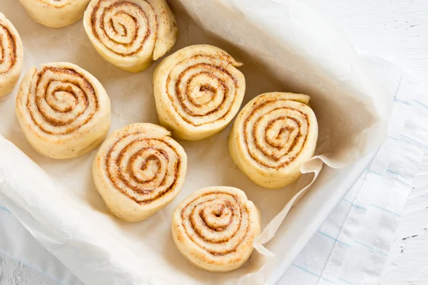 Rulo tarçın veya cinnabon, ev yapımı tarifi çiğ hamur hazırlık tatlı geleneksel tatlı çörekler pasta yemek pişirme tepsisi üzerinde.