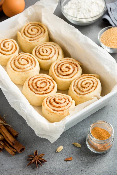 Rulo tarçın veya cinnabon, ev yapımı tarifi çiğ hamur hazırlık şekerli geleneksel tatlı çörek tepsisi üzerinde pişirme üzerinde pasta malzemeler gıda ile arka plan gri.