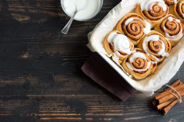 Rulo tarçın veya cinnabon soslu, ev yapımı geleneksel tatlı çörekler pasta yemek kopya alanı koyu ahşap zemin üzerine.