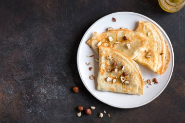 Krep Suzette bal ve fındık koyu arka plan üzerinde beyaz tabakta ile alanı kopyalayın. Kahvaltı için lezzetli ev yapımı krep.