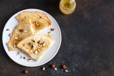 Krep Suzette bal ve fındık koyu arka plan üzerinde beyaz tabakta ile alanı kopyalayın. Kahvaltı için lezzetli ev yapımı krep.