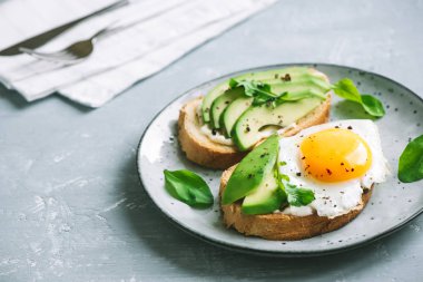 Sahanda yumurta - dilimlenmiş avokado ve roka için sağlıklı kahvaltı veya aperatif, kızarmış ekmek üzerinde yumurta ile avokado sandviç kopyalama alanı.