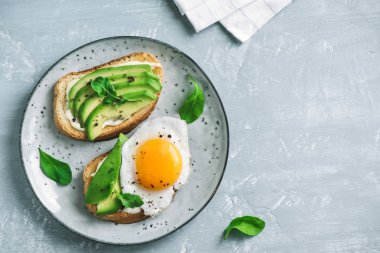 Sahanda yumurta - dilimlenmiş avokado ve roka için sağlıklı kahvaltı veya aperatif, kızarmış ekmek üzerinde yumurta ile avokado sandviç kopyalama alanı.