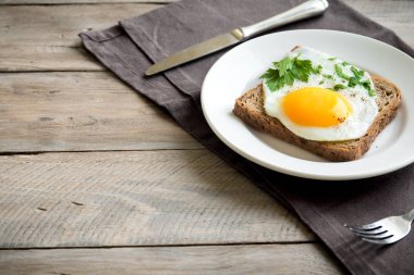 Tost kahvaltıda sahanda yumurta. Sahanda yumurta ekmek ve ahşap masa, üstten görünüm, kopya alanı beyaz tabakta maydanoz ile.