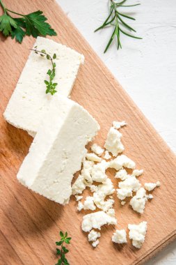 Taze Yunan beyaz peynir. Salata yemek için sağlıklı bir madde. Ufalanmış keçi beyaz peynir kesme tahtası üzerinde.