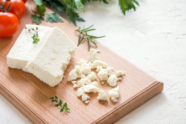 Taze Yunan beyaz peynir. Salata yemek için sağlıklı bir madde. Ufalanmış keçi beyaz peynir kesme tahtası üzerinde.