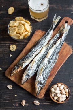 Çeşitli aperatifler bira için: güneş kurutulmuş balık, fındık, tuzlu kruton veya kraker ahşap arka plan, üstten görünüm üzerinden kopyalama alanı. Lager bira ve kurutulmuş gölde aperatifler.