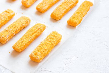 Kızarmış balık, Balık kroket kağıt ve beyaz arka plan, donmuş alanı kopyalayın. Rahatlık gıda, deniz ürünleri, balık yemek çubukları kroket.