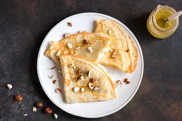 Krep Suzette bal ve fındık koyu arka plan üzerinde beyaz tabakta ile alanı kopyalayın. Kahvaltı için lezzetli ev yapımı krep.