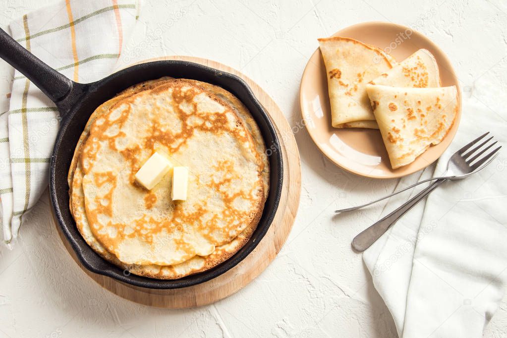 Homemade crepes with butter in cast iron pan over white background  - cooking fresh homemade breakfast crepes pancakes food