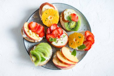 Ricotta peynirli meyve tatlı sandviç. Lezzetli sağlıklı kahvaltı tost ile krem peynir, taze organik meyve ve çilek, otlar, fındık ve arı polen. Diyet sağlıklı yemek, Kahvaltı, snack.