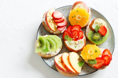 Ricotta peynirli meyve tatlı sandviç. Lezzetli sağlıklı kahvaltı tost ile krem peynir, taze organik meyve ve çilek, otlar, fındık ve arı polen. Diyet sağlıklı yemek, Kahvaltı, snack.