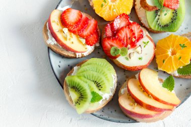 Ricotta peynirli meyve tatlı sandviç. Lezzetli sağlıklı kahvaltı tost ile krem peynir, taze organik meyve ve çilek, otlar, fındık ve arı polen. Diyet sağlıklı yemek, Kahvaltı, snack.