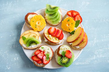 Ricotta peynirli meyve tatlı sandviç. Lezzetli sağlıklı kahvaltı tost ile krem peynir, taze organik meyve ve çilek, otlar, fındık ve arı polen. Diyet sağlıklı yemek, Kahvaltı, snack.