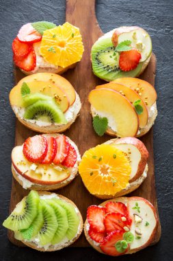 Ricotta peynirli meyve tatlı sandviç. Lezzetli sağlıklı kahvaltı tost ile krem peynir, taze organik meyve ve çilek, otlar, fındık ve arı polen. Diyet sağlıklı yemek, Kahvaltı, snack.