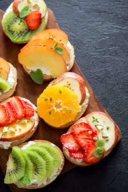 Meyve tatlı sandviç ya da bruschetta ricotta peynirli. Lezzetli sağlıklı kahvaltı tost ile krem peynir, organik meyve ve çilek, otlar, fındık ve arı polen. Diyet sağlıklı yemek, Kahvaltı, snack.