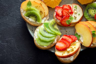 Meyve tatlı sandviç ya da bruschetta ricotta peynirli. Lezzetli sağlıklı kahvaltı tost ile krem peynir, organik meyve ve çilek, otlar, fındık ve arı polen. Diyet sağlıklı yemek, Kahvaltı, snack.