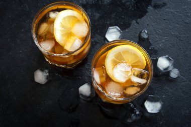 Soğuk buzlu çay limon ve buz küpleri ile siyah taş zemin, kopya alanı, üstten görünüm. Buzlu yaz içeceği.