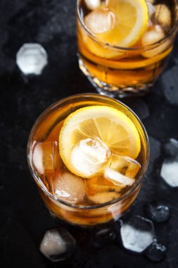 Soğuk buzlu çay limon ve buz küpleri ile siyah taş zemin, kopya alanı, üstten görünüm. Buzlu yaz içeceği.