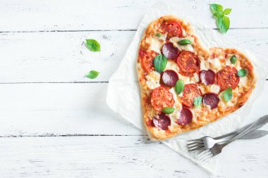 Kalp kopya alanı ile ahşap arka plan üzerinde pizza şeklinde. Pizza domates, biber, mozzarella peyniri ve Sevgililer günü için fesleğen ile.