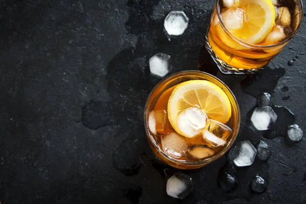 Soğuk buzlu çay limon ve buz küpleri ile siyah taş zemin, kopya alanı, üstten görünüm. Buzlu yaz içeceği.