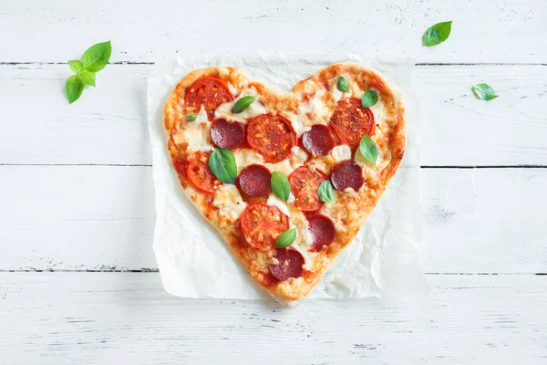 Kalp kopya alanı ile ahşap arka plan üzerinde pizza şeklinde. Pizza domates, biber, mozzarella peyniri ve Sevgililer günü için fesleğen ile.