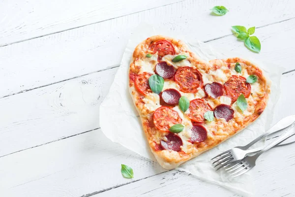 Kalp kopya alanı ile ahşap arka plan üzerinde pizza şeklinde. Pizza domates, biber, mozzarella peyniri ve Sevgililer günü için fesleğen ile.