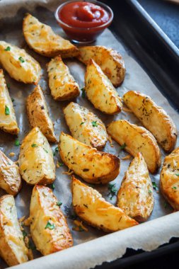 Patates dilimleri ile baharat, peynir ve fırın tepsisi ve Domates ketçap - otlar pişmiş ev yapımı organik sebze vegan vejetaryen snack gıda.