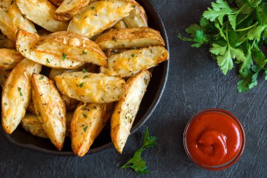 Patates dilimleri peynir ve ot ve siyah arka plan - üzerine domates sosu ile pişmiş ev yapımı organik sebze vegan vejetaryen patates dilimleri aperatif yemek yemek.