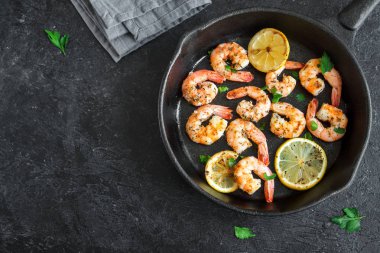 Limon, sarımsak ve otlar ile Kızarmış karides. Deniz ürünleri, shelfish. Baharat, sarımsak ve limon siyah taş zemin, kopya alanı üzerine karides karides ızgara. Karides karides dökme demir Pan. 