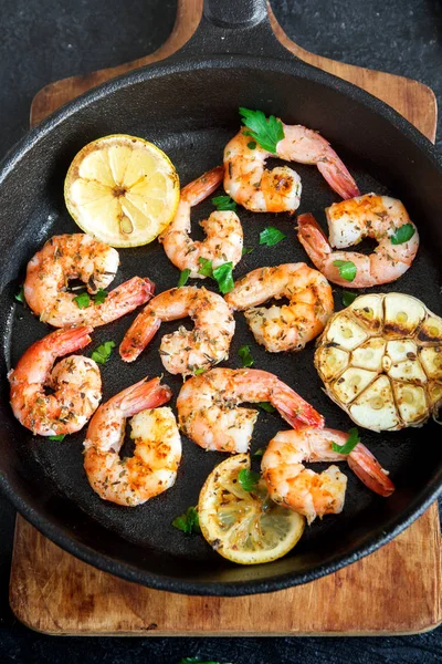 Limon, sarımsak ve otlar ile Kızarmış karides. Deniz ürünleri, shelfish. Baharat, sarımsak ve limon siyah taş zemin, kopya alanı üzerine karides karides ızgara. Karides karides dökme demir Pan.