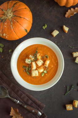 Balkabağı çorbası ve organik kabaklar, üstten görünüm. Mevsim sonbahar gıda - baharatlı balkabağı çorbası kruton ve kabak çekirdeği ile.