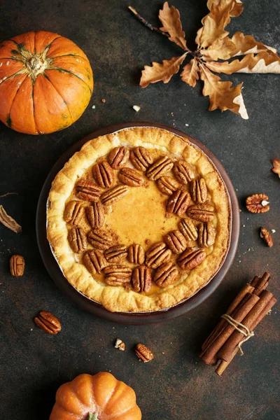 Pumpkin and Pecan Pie with cinnamon on rustic background, top view, copy space. Homemade autumn pastry for Thanksgiving.