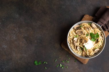 Mantar spagetti makarna ve krema sos rustik arka planda, üstten görünüm alanı kopyalayın. Pan pişirme champignon mantarlı ev yapımı makarna çeşitleri.