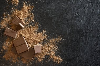 Kırık siyah çikolata parçaları ve kakao tozu. Çikolata onr koyu taş arka plan topakları.