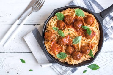 Köfte, domates sos ve taze fesleğen dökme demir tavada spagetti makarna. Beyaz ahşap arka plan kopya alanı ile sağlıklı ev yapımı İtalyan Makarna.