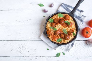 Köfte, domates sos ve taze fesleğen dökme demir tavada spagetti makarna. Beyaz ahşap arka plan kopya alanı ile sağlıklı ev yapımı İtalyan Makarna.