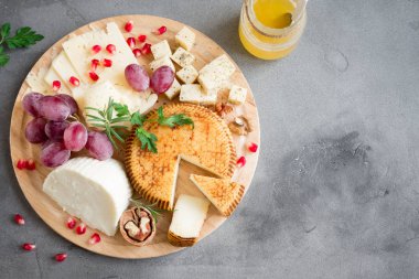 Peynir tabağı ile çeşitli peynirler, üzüm, fındık gri taş zemin, kopya alanı üzerinde. İtalyan peynir ve meyve tabağı.