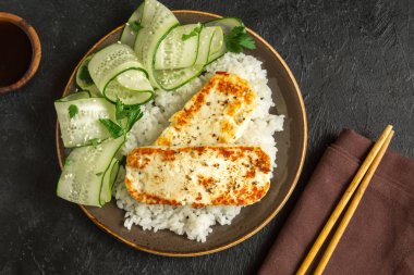 Pirinç ve salatalık salatası siyah arka plan, tofu biftek alanı kopyalayın. Kavrulmuş kızarmış tofu biftek ile sağlıklı vegan vejetaryen yemek yemek.