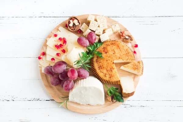 Cheese platter with assorted cheeses, grapes, nuts on white background, copy space. Italian cheese and fruit platter.