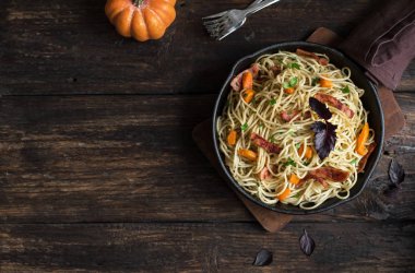 Kabak ve dökme demir tavada pastırma ile sonbahar makarna. Ahşap ev yapımı spagetti kabak makarnaya, kopya alanı. Sonbahar mevsimlik gıda.