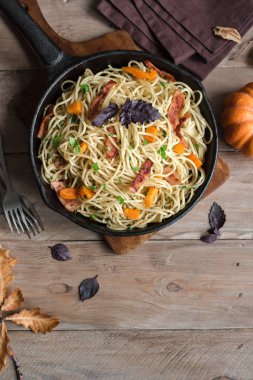 Kabak ve dökme demir tavada pastırma ile sonbahar makarna. Ahşap ev yapımı spagetti kabak makarnaya, kopya alanı. Sonbahar mevsimlik gıda.