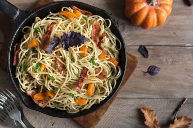 Kabak ve dökme demir tavada pastırma ile sonbahar makarna. Ahşap ev yapımı spagetti kabak makarnaya, kopya alanı. Sonbahar mevsimlik gıda.