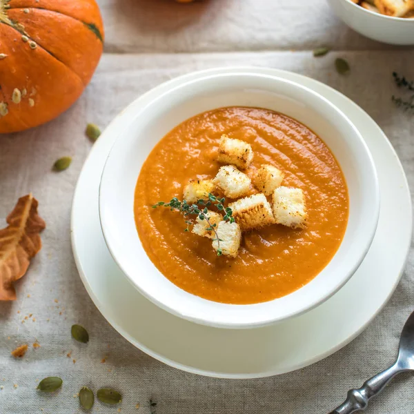 Pumpkin soup and organic pumpkins, top view. Seasonal autumn food - Spicy pumpkin soup with croutons.