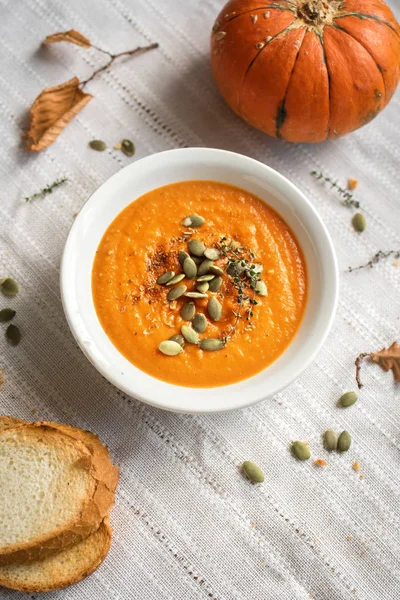 Pumpkin soup and organic pumpkins, top view. Seasonal autumn food - Spicy pumpkin soup with croutons.