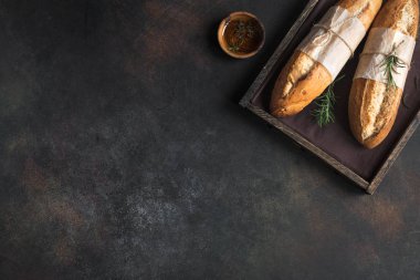 Biberiye ve rustik ahşap kutusunda, üstten görünüm sızma zeytinyağı ile taze ev yapımı ekmek. Maya mini baget ekmek.