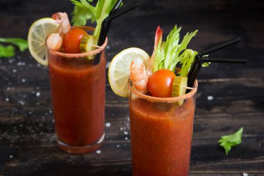 Kokteyl Bloody Mary garnitürleri ile gözlük. Koyu ahşap arka plan kopya alanı ile domates Bloody Mary baharatlı içki.