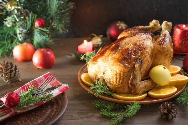 Roasted Christmas Chicken or Turkey for Christmas Dinner. Festive decorated wooden table for Christmas Dinner with baked chicken.